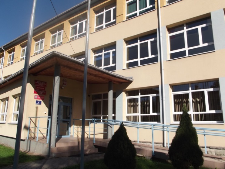 Trzykondygnacyjny budynek o jasnej elewacji z dużymi prostokątnymi oknami. Wejście główne z daszkiem wspartym na słupach. Przy wejściu podjazd dla osób z niepełnosprawnościami i tablice informacyjne.